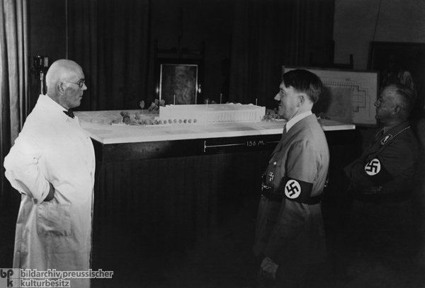 Der Architekt Paul Ludwig Troost mit Hitler und Gauleiter Adolf Wagner vor dem Modell des Hauses der Deutschen Kunst (1933)
