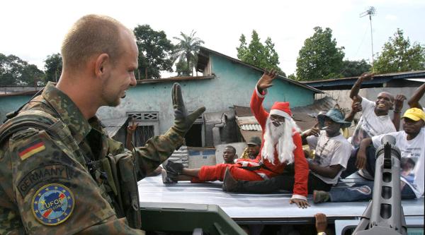 Ein Fallschirmjäger der Bundeswehr winkt bei einer Patrouille Bewohnern der Stadt Kinshasa zu (26. Oktober 2006)